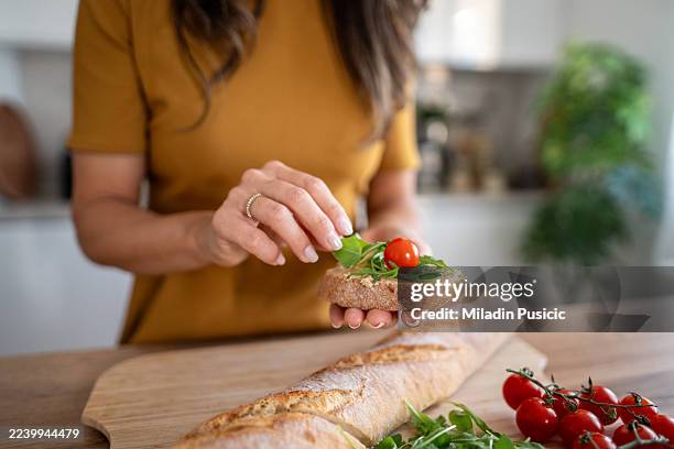 woman preparing healthy baguette sandwich with fresh vegetables - making a sandwich stock pictures, royalty-free photos & images