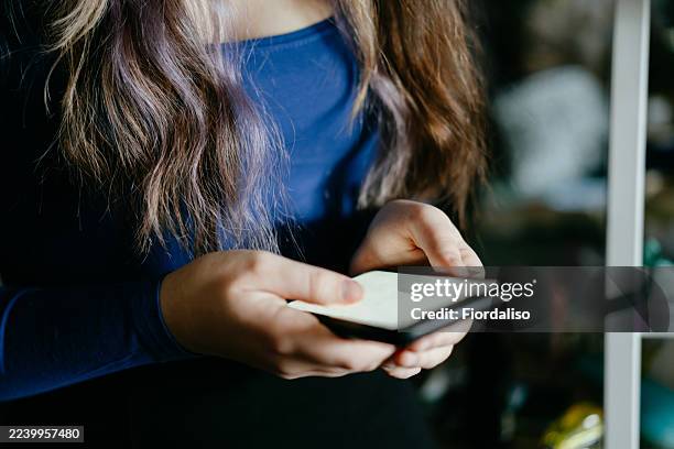 person using smartphone indoors with blue top, close-up of hands on device - mishandeling stockfoto's en -beelden