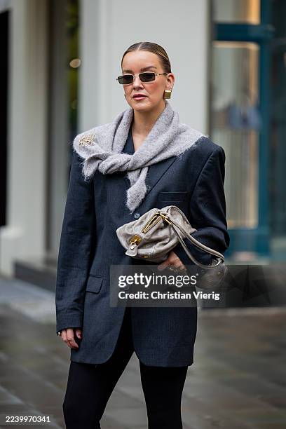 Tina Haase wears vintage black oversize blazer, Black stirrup leggings, taupe knit triangle scarf Massimo Dutti, Loewe brooch, taupe grey Prada Bag...