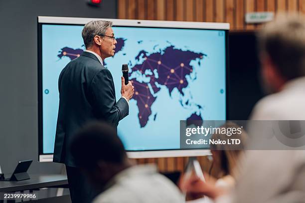 man presenting global business strategy with world map - complex world stock pictures, royalty-free photos & images