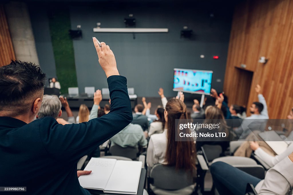 Audience raising hands during business conference presentation