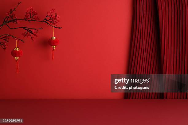 Traditional red lanterns with cherry blossoms on pleated fabric background. Elegant Chinese New Year decor with cultural symbolism.