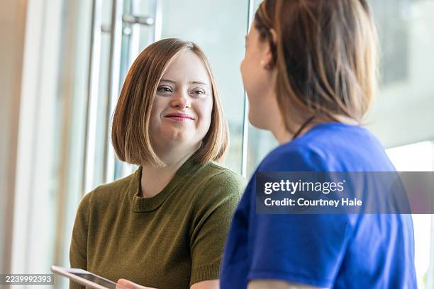young adult woman with down syndrome and doctor review chart together - down syndrome stock pictures, royalty-free photos & images