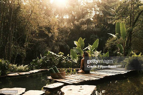 woman meditating in tropical jungle spa retreat - kuuroord stockfoto's en -beelden