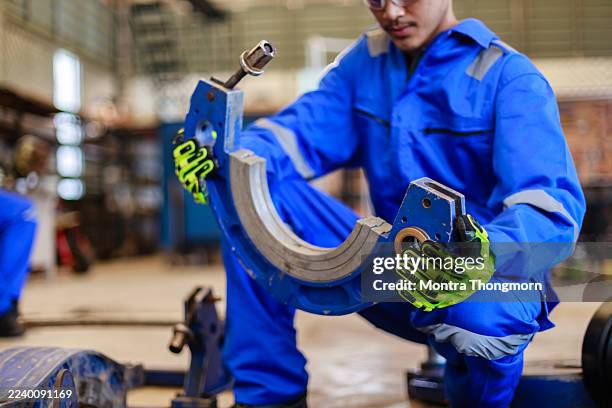 close-up of an engineer in blue uniform and safety gloves adjusting a pipe clamping fixture for hdpe welding in an industrial setting. concept of precision work, safety, and mechanical setup - automatic welding torch stock pictures, royalty-free photos & images