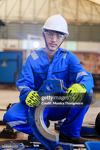 close-up of an engineer in blue uniform and safety gloves adjusting a pipe clamping fixture for hdpe welding in an industrial setting. concept of precision work, safety, and mechanical setup - automatic welding torch stock pictures, royalty-free photos & images