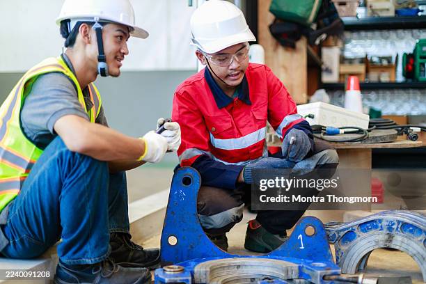 two engineers in safety uniforms working together to adjust a pipe clamping fixture in a workshop, focusing on teamwork, precision, and preparation in industrial pipe welding or installation tasks - automatic welding torch stock pictures, royalty-free photos & images