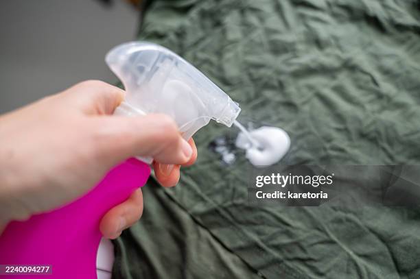 hand spraying stain remover on clothes - removing stock pictures, royalty-free photos & images