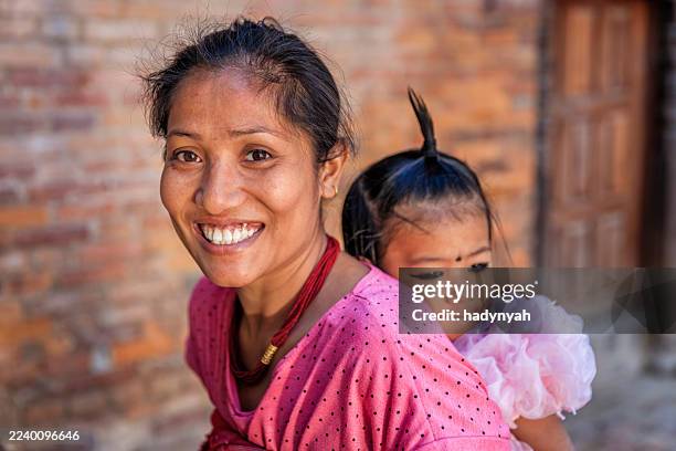 nepali young woman carrying her little daughter, bhaktapur, nepal - nepal family stock pictures, royalty-free photos & images