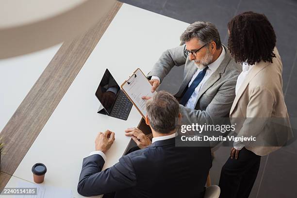 business colleagues reviewing contract documents in office meeting - relatório financeiro imagens e fotografias de stock