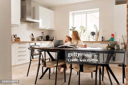 Family at home: Scandinavian mother and child study while working on a laptop in the kitchen Family at home: Scandinavian mother and child study while working on a laptop in the kitchen
