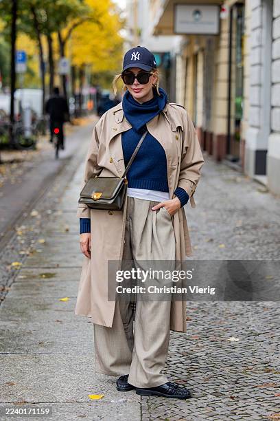 Victoria Scheu wears beige wide leg pants H&M, blue knit Ssezane, beige trench coat, knitted scarf Sezane, black loafers with fringes Flattered,...