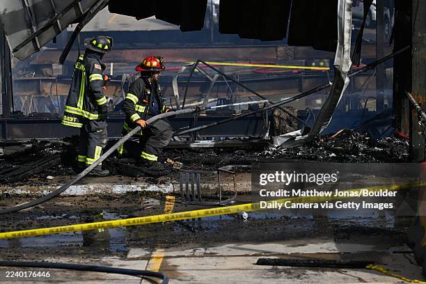 Firefighters continue to work to extinguish hot spots in a fire in the Caribou Village Shopping Center in Nederland on Thursday, Oct. 9, 2025.