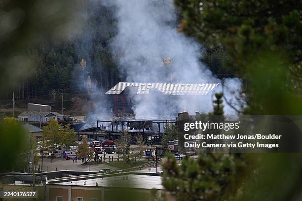 Smoke rises from the debris as firefighters continue to work to extinguish hot spots in a fire in the Caribou Village Shopping Center in Nederland on...