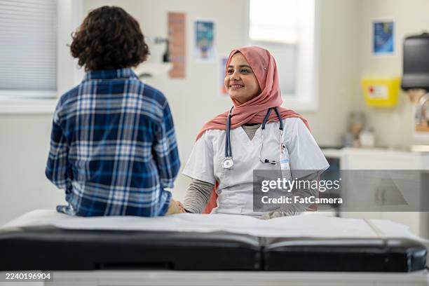 female hijab-wearing nurse comforts patient in clinic with stethoscope and friendly smile - neurodiversity stock pictures, royalty-free photos & images