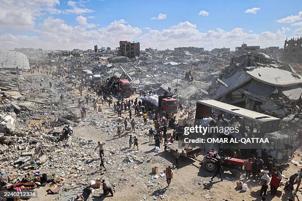 Palestinians rally around aid trucks which entered from the Karem Abu Salem crossing, in Khan Yunis in the southern Gaza Strip on October 12 as a...