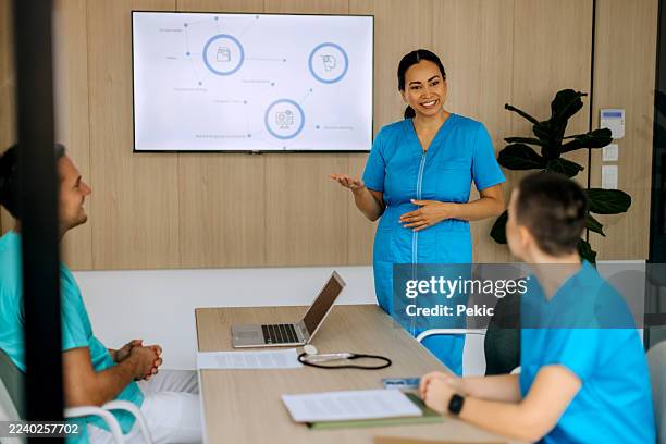 mid-adult doctor leading meeting in conference room - medical procedure stock pictures, royalty-free photos & images
