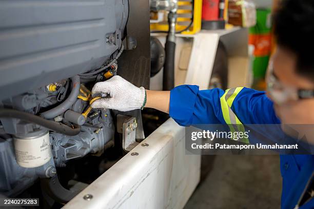 a blue-collar engineer in safety uniform and gloves examines motor oil level using a measurement tool inside an aircraft maintenance station. concept of quality control, lubrication, repair service, mechanical equipment, industrial expertise, and safety - lubrication stock pictures, royalty-free photos & images