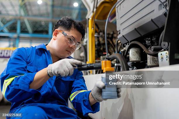 un técnico de cuello azul con equipo de seguridad utiliza un tubo de bomba de aceite para recolectar aceite de motor para análisis químico y control de calidad. concepto de lubricación, servicio de reparación, mantenimiento industrial, inspección de - lubricación fotografías e imágenes de stock