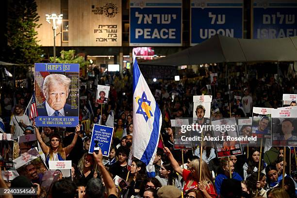 People hold up posters of U.S. President Donald Trump and hostages as they wait for the start of the hostage release live stream at Hostages Square...