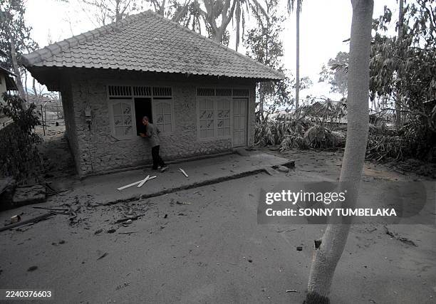 An elderly Indonesian villager checks his ash covered home as Mount Merapi volcano continues spewing clouds of hot ash at the village of Umbulharjo...