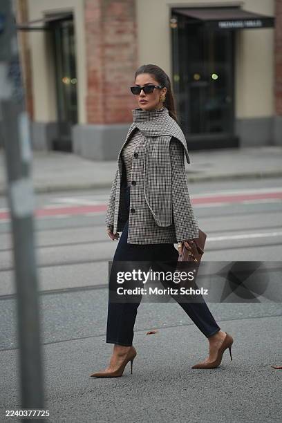 Füsun Lindner is seen wearing a checked long-sleeved top in neutral tones, featuring a fitted silhouette and thumbhole sleeves from COS; a...