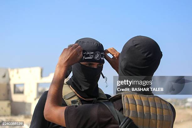 Palestinian militant fighter of the Ezzedine al-Qassam Brigades, the armed wing of the Palestinian Hamas movement, fixes the headband of the group on...