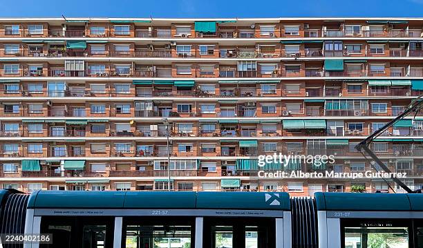 urban apartment building facade with green awnings and passing tram illustrating city living and public transport - awning stock pictures, royalty-free photos & images