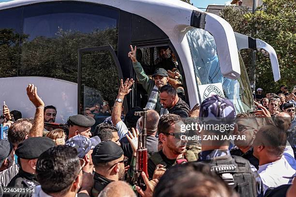 One of the Palestinian prisoners, who was released in a prisoner-hostage swap and ceasefire deal between Israel and Hamas, gestures as he and others...