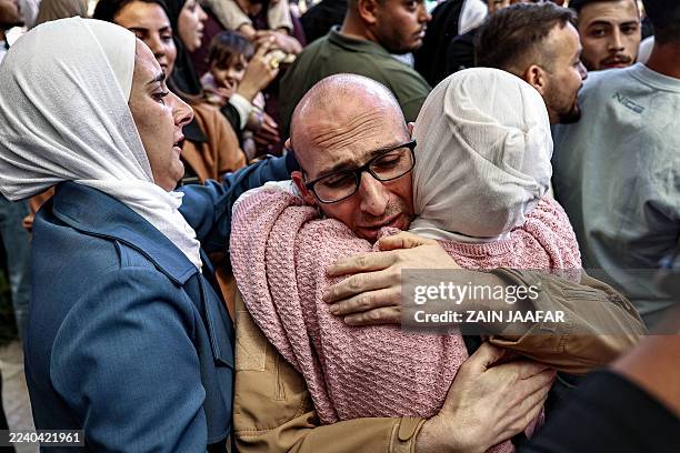One of the Palestinian prisoners, who was released in a prisoner-hostage swap and ceasefire deal between Israel and Hamas, is embraced by a woman...