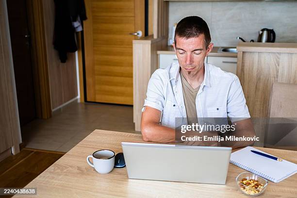 day in the life of man with diabetes working from home on laptop. man is wearing small sensor, medical alert device for blood glucose monitoring on the back of upper arm. - type 1 diabetes stock pictures, royalty-free photos & images