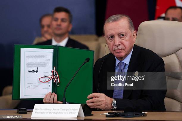 Turkish President Tayyip Erdogan poses with the signed agreement at a world leaders' summit on ending the Gaza war on October 13, 2025 in Sharm...