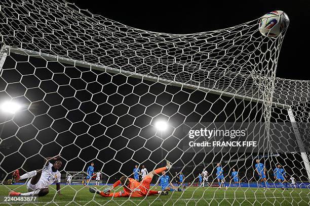 France's forward Jean-Philippe Mateta scores his team's second goal past Iceland's goalkeeper Elias Rafn Olafsson during the 2026 World Cup...