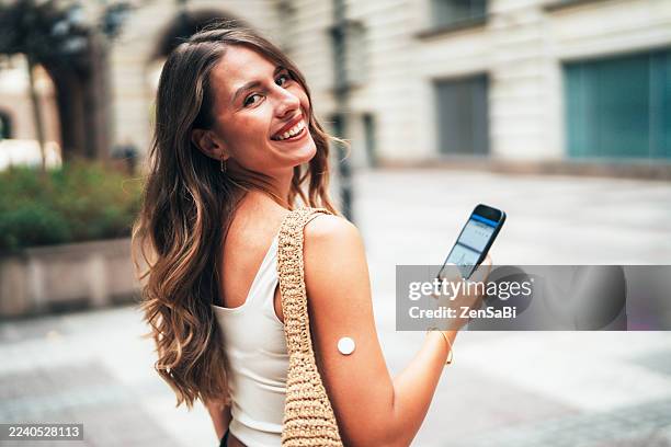 young woman using diabetes sensor and smartphone app for glucose monitoring - glucose stockfoto's en -beelden