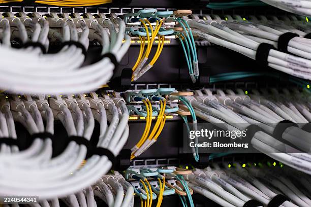 Fiber optic cables, center, and copper Ethernet cables feed into switches inside a communications room at an office in London, UK, on Monday, Oct....