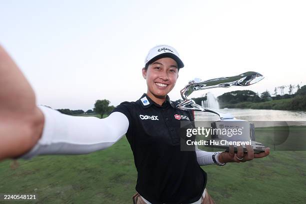 Jeeno Thitikul of Thailand imitates a “selfie” as she poses with the trophy after winning the the final round of the Buick LPGA Shanghai 2025 at...