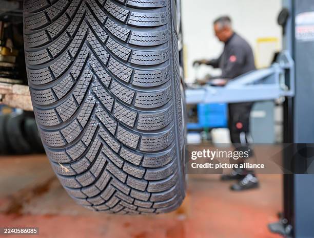 October 2025, Brandenburg, Frankfurt : A winter tire is fitted to a car in a workshop. There is no fixed date for changing from summer to winter...