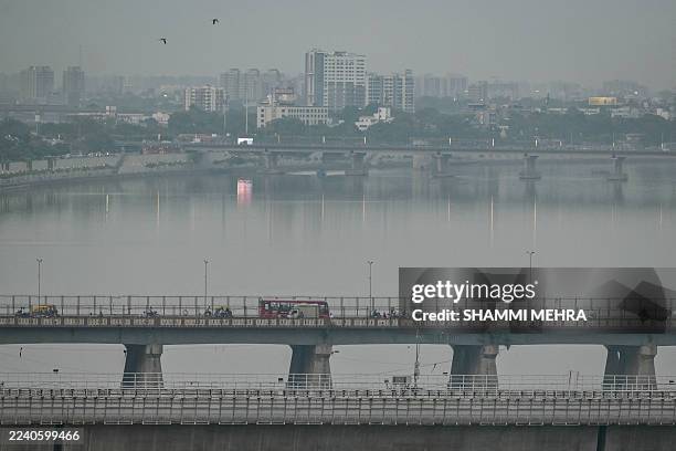 Vehicles move past over a bridge at the Sabarmati riverfront area on a hazy day in Ahmedabad on October 14, 2025.