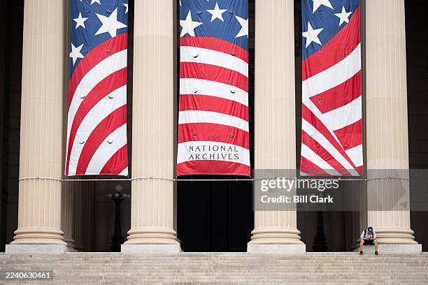 Man sits outside of the National Archives building, which is closed is closed during the federal government shutdown, in Washington on Tuesday,...
