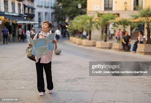 senior asian woman exploring city street with map - lost stock pictures, royalty-free photos & images
