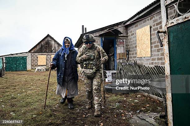 Police officer from the ''White Angel'' special unit escorts a 93-year-old woman by the arm to an armored minibus during the evacuation of residents...