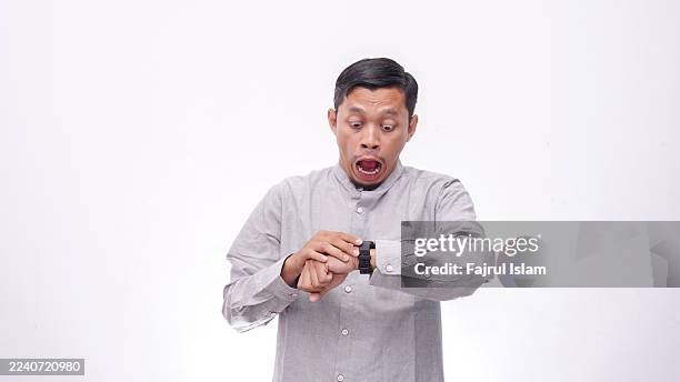 shocked asian man looking his smartwatch against white background - checking the time stock pictures, royalty-free photos & images