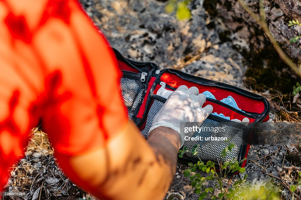 Mountain Rescuer Reaching For A First Aid Kit On The Mountain