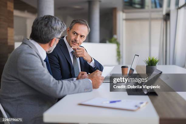 businessmen discussing documents during an office meeting - team commitment stock pictures, royalty-free photos & images