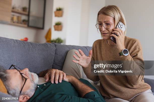 ehefrau ruft nothilfe für bewusstlosen ehemann - rettungsdienst stock-fotos und bilder