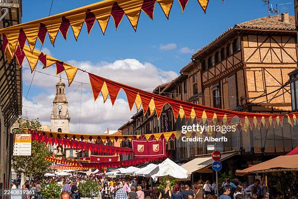 la gente visita el mercado medieval en un pueblo decorado con telas y puestos en toro, zamora. - medieval fotografías e imágenes de stock