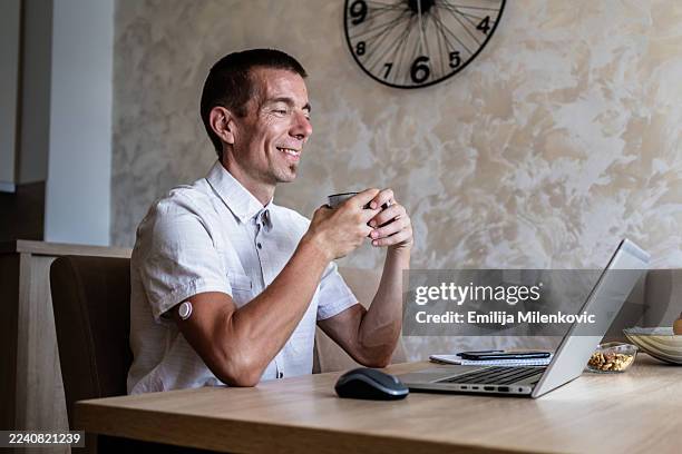 day in the life of man with diabetes working from home and having online video call on laptop. man is wearing small sensor, medical alert device for blood glucose monitoring on the back of upper arm. - type 1 diabetes stock pictures, royalty-free photos & images