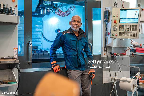 mature hispanic technician confidently leaning on cnc machine in workshop - moulding machine stock pictures, royalty-free photos & images