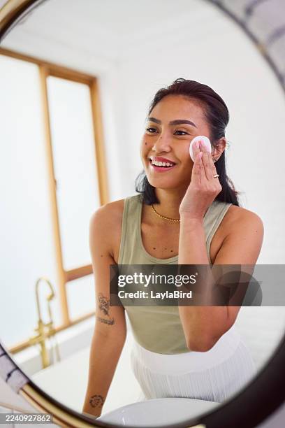 happy asian woman applying toner with cotton pad in mirror - facial cleanser stock pictures, royalty-free photos & images