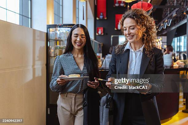 two professional women enjoying a lunch break in a self-service restaurant - buffet stockfoto's en -beelden